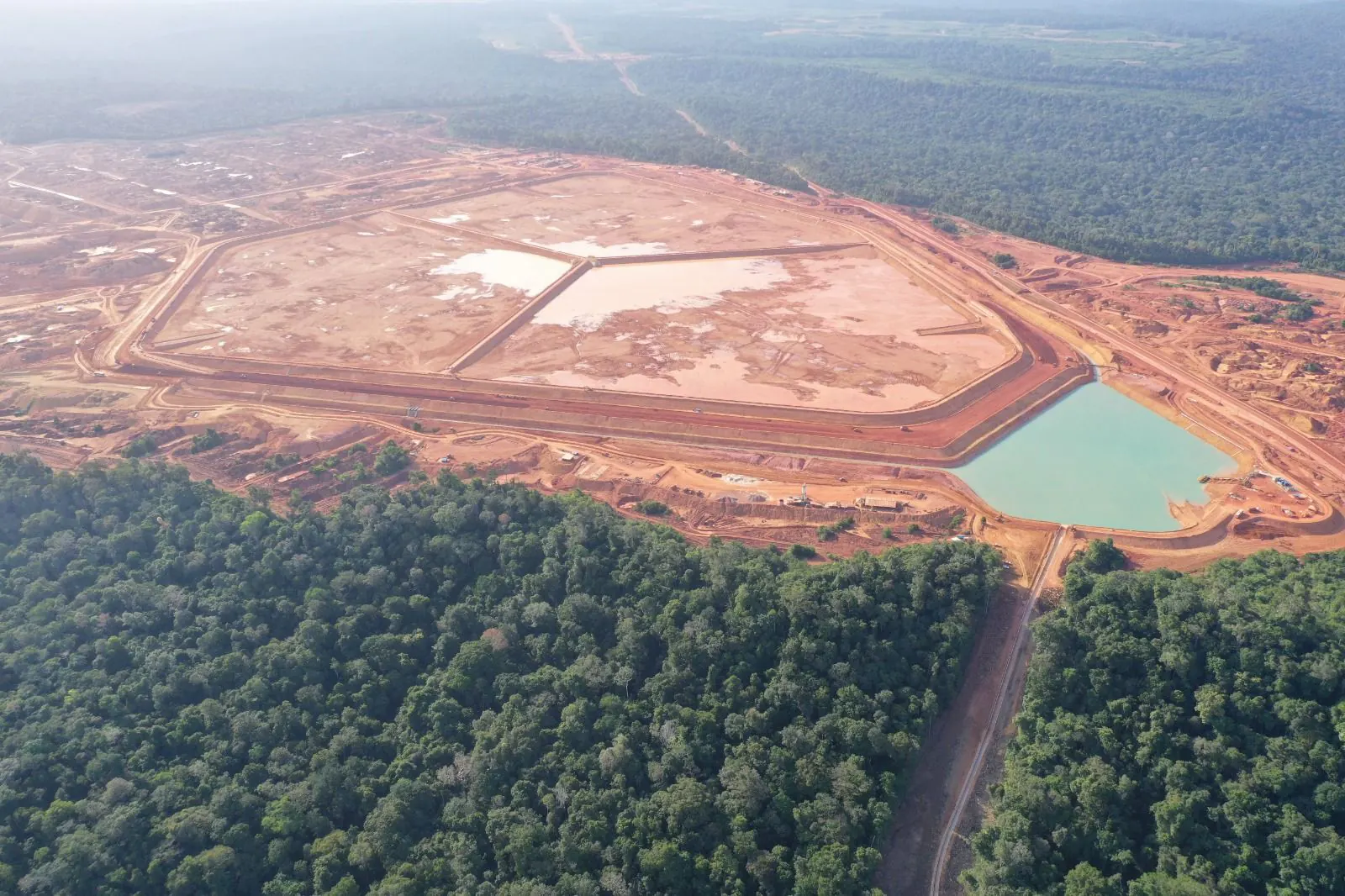 Vista aérea da Barragem SP-25 com lagoa esverdeada, cercada por floresta