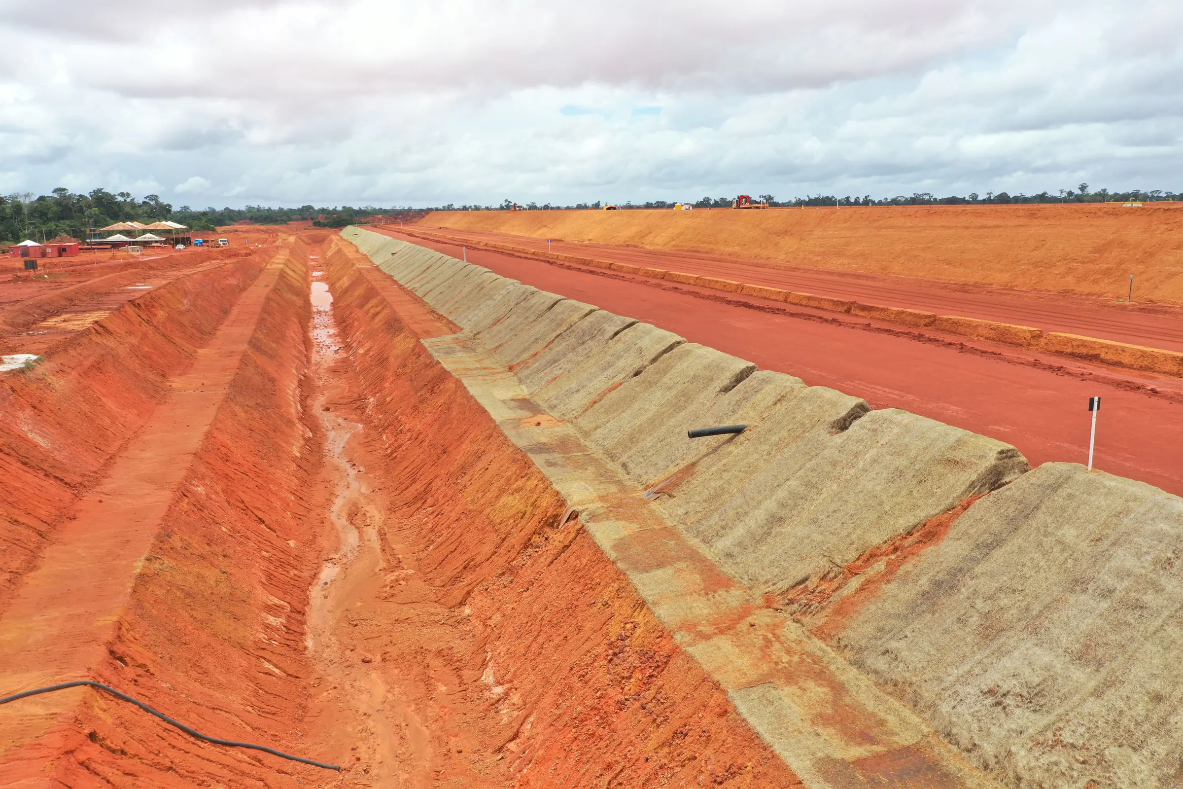 Talude da Barragem SP24 em bermas sucessivas, com a crista em terra vermelha e o canal de drenagem ao pé