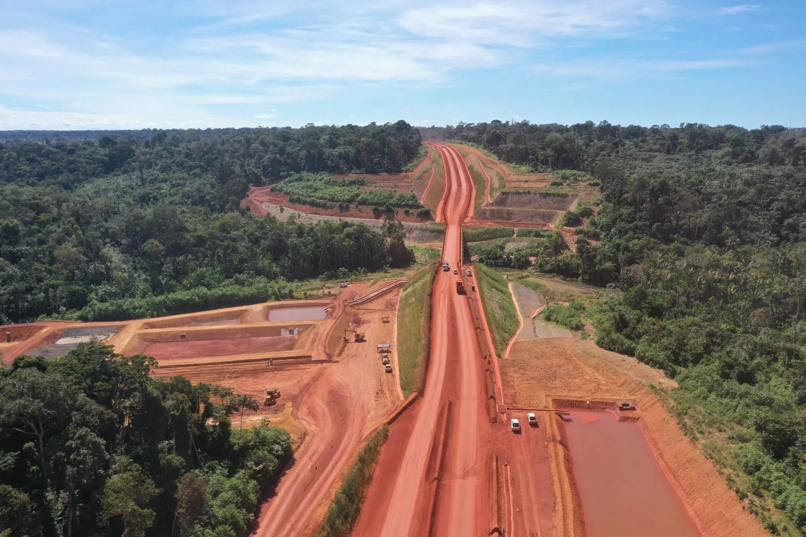 Estrada de terra vermelha cortando a floresta, vista do alto