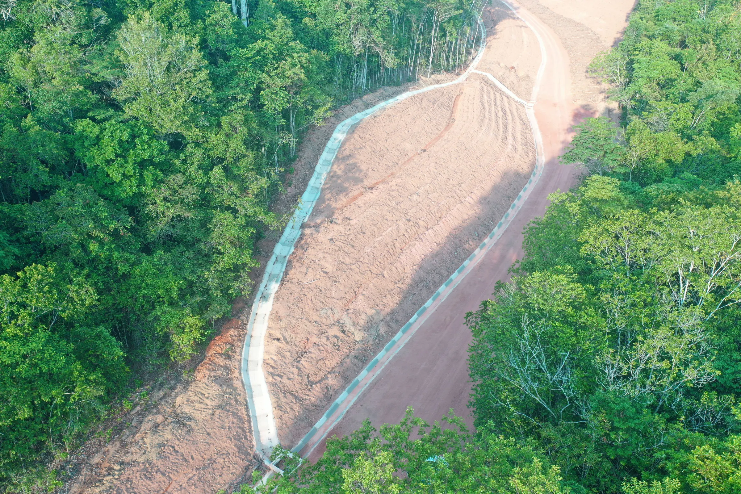 Vista aérea de talude conformado com canaleta de concreto, em faixa aberta na floresta